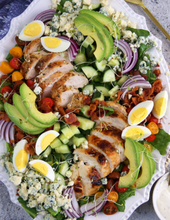 A cobb salad is plated on a large white serving plate.