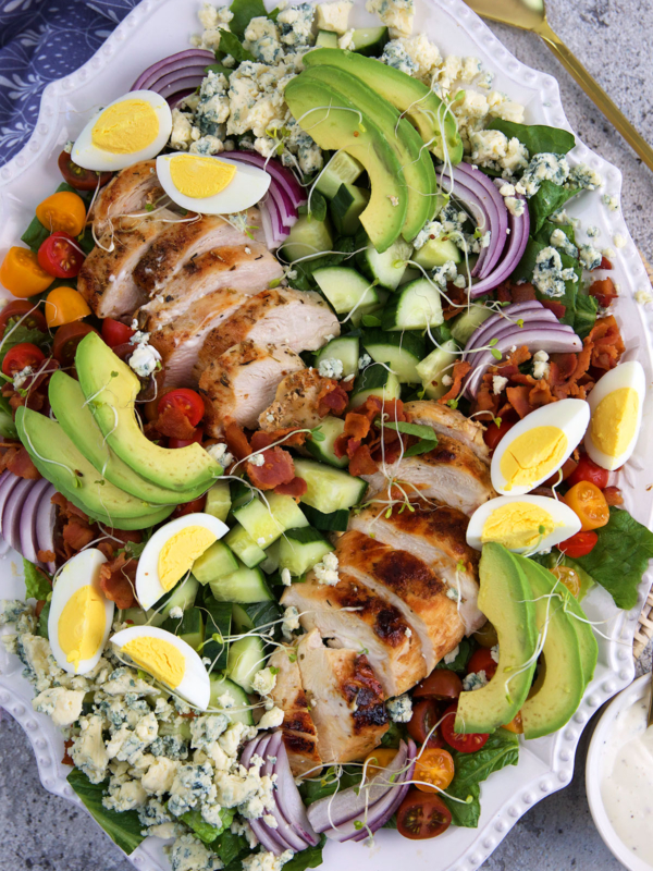 A cobb salad is plated on a large white serving plate.