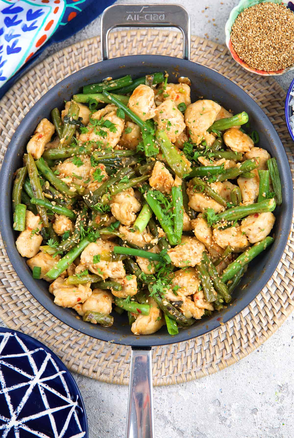 A skillet is filled with green beans, onions, and cooked chicken.