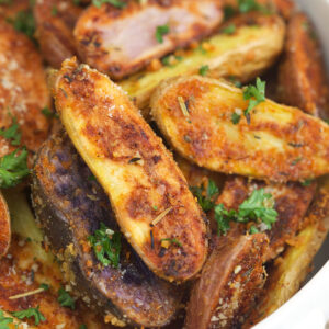 Roasted fingerling potatoes are garnished with parsley.