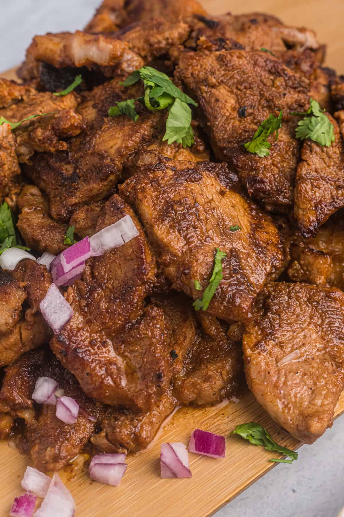 Cooked pork is topped with red onions and cilantro. 