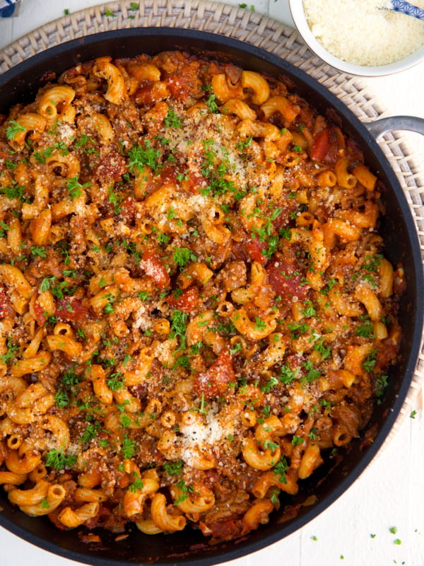 A large black skillet is filled with cooked beefaroni.