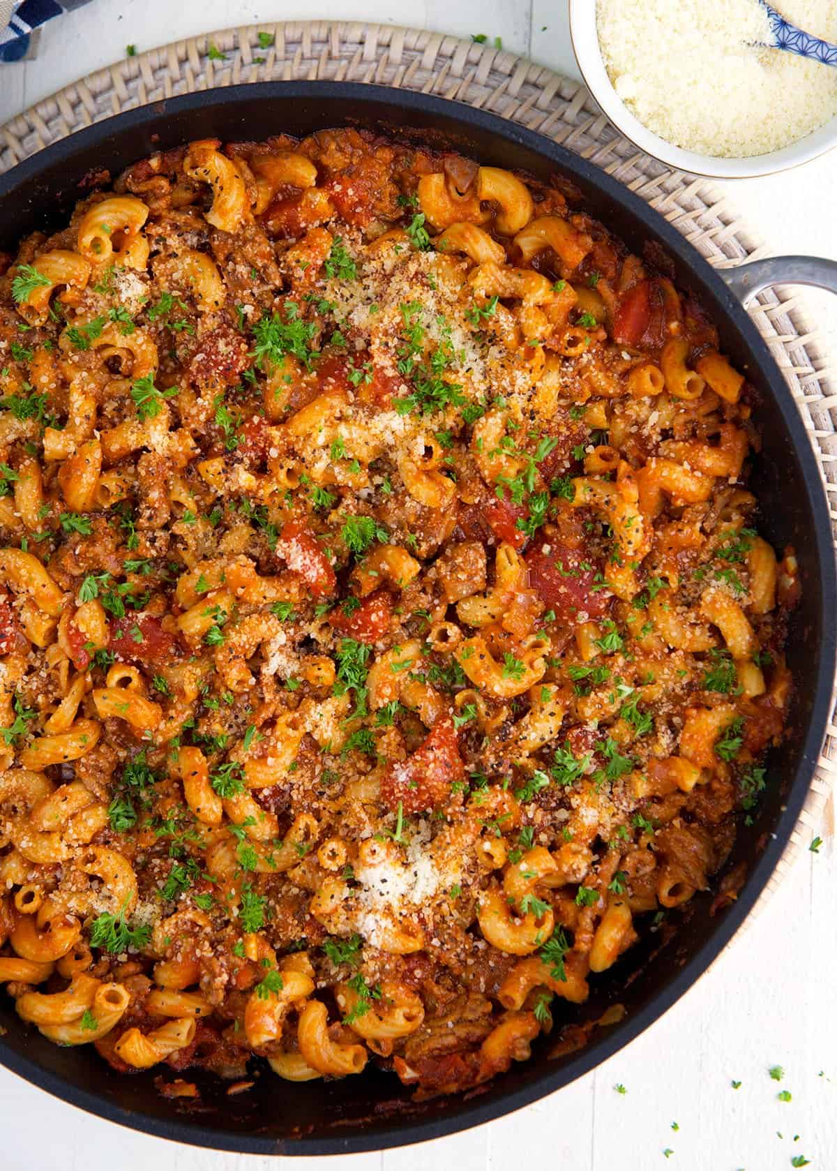 A large black skillet is filled with cooked beefaroni.