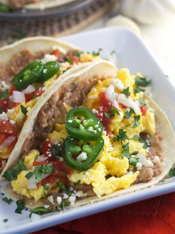 Two tacos are placed on a square white plate.