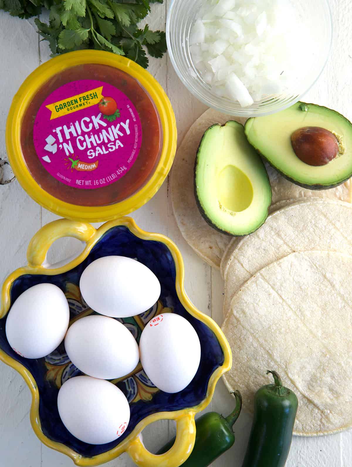 The ingredients for breakfast tacos are placed on a white surface.
