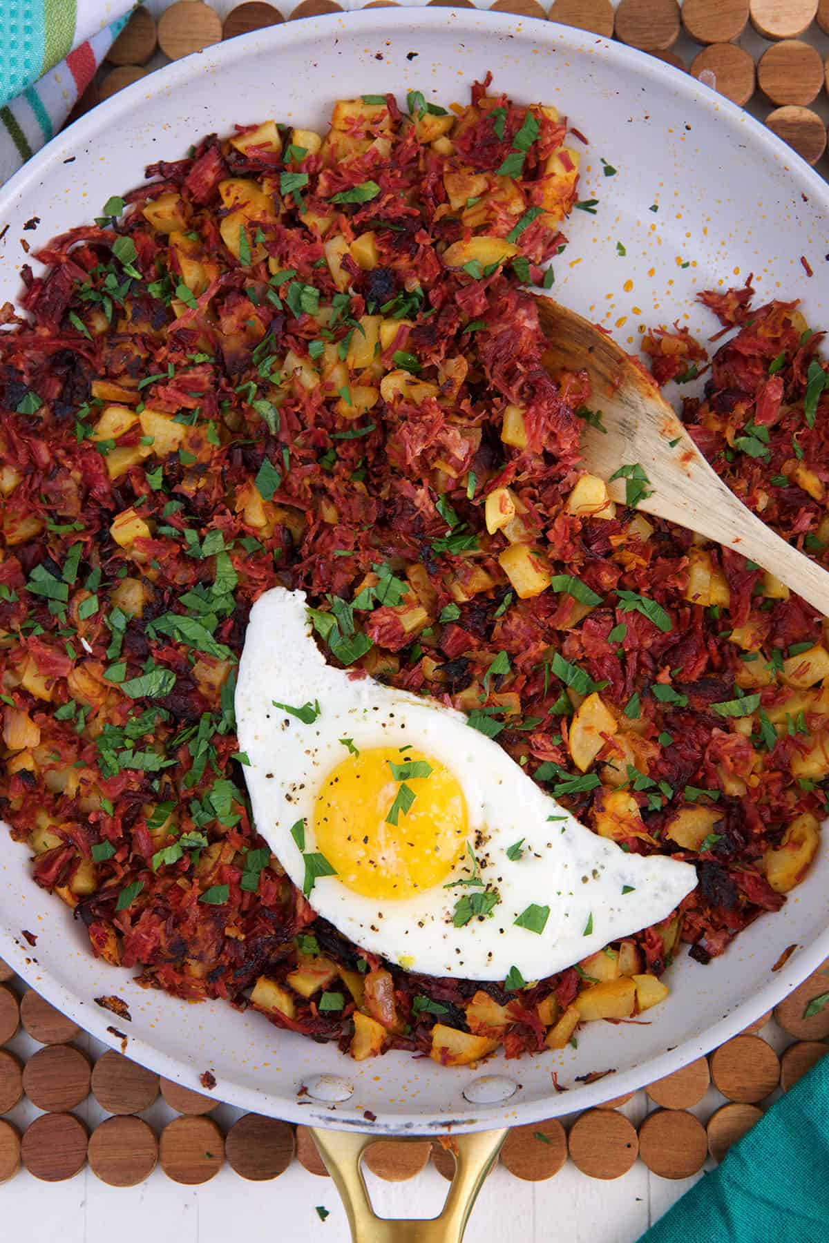 A fried egg is placed in a skillet with corned beef hash.
