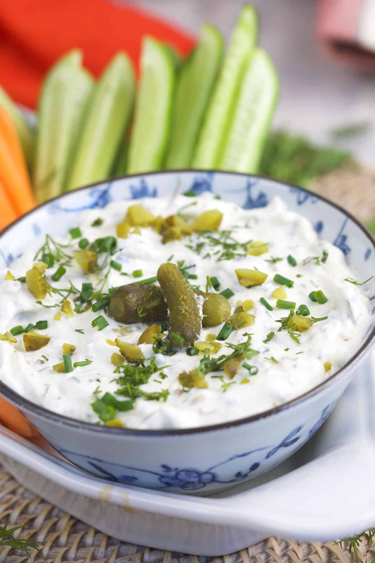 A blue and white bowl is filled with dill pickle dip.