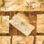 Slices of focaccia are placed on a wooden cutting board.
