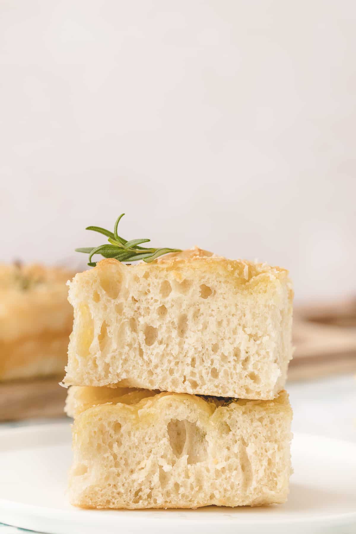 Two pieces of focaccia bread are placed on a white surface.