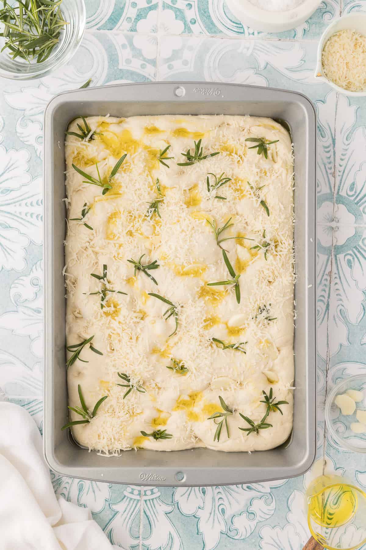 A baking pan is filled with uncooked focaccia. 