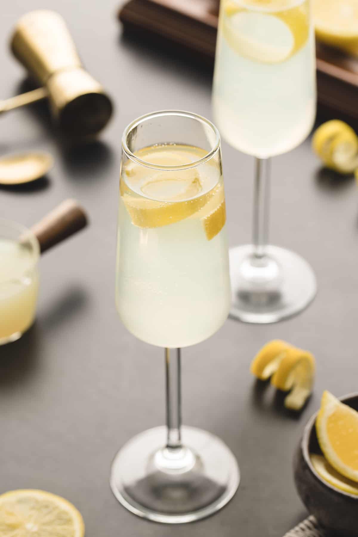 A glass of french 75 is garnished with a lemon peel. 