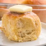 A square of butter is melting on top of a baked roll.