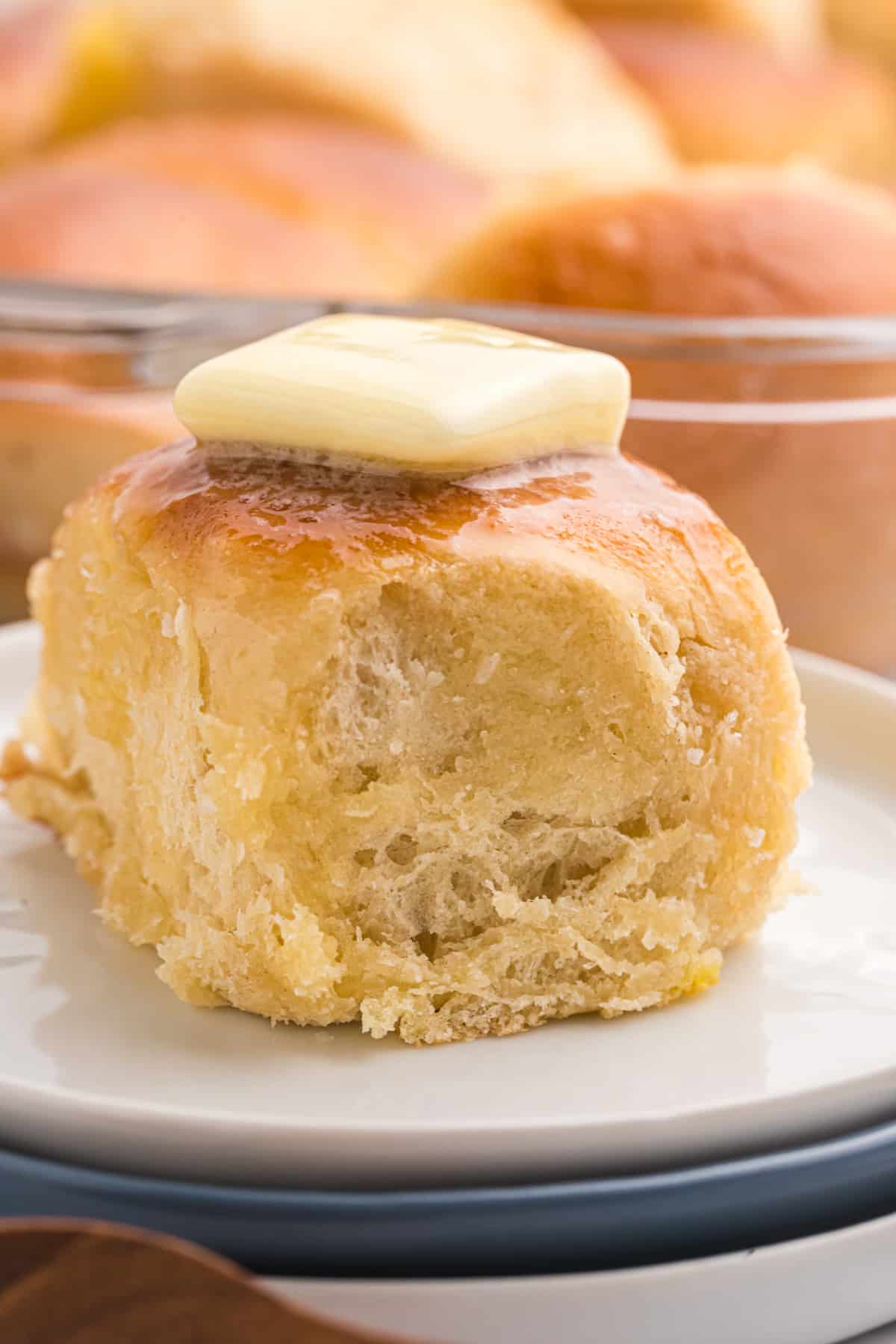 A square of butter is melting on top of a baked roll. 