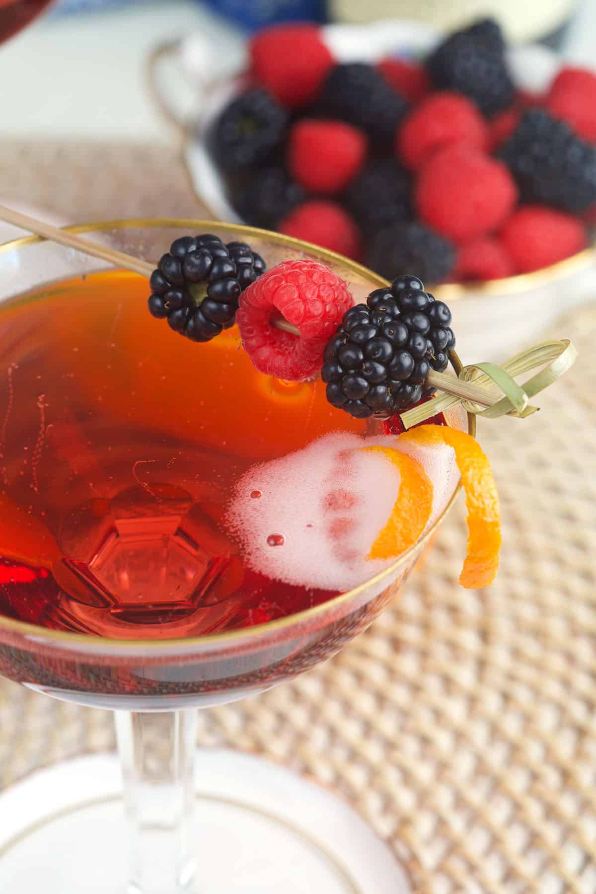 Berries and an orange peel garnish a glass of Kir Royale.