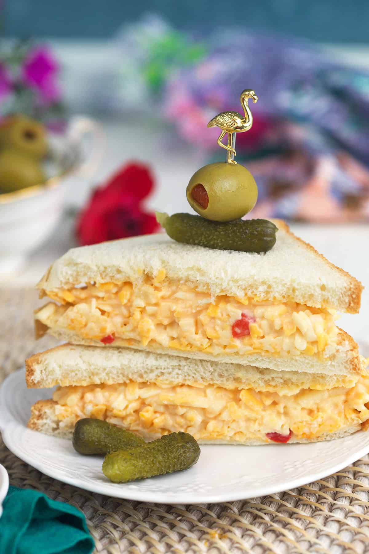 Pickles and olives garnish a pimento cheese sandwich.