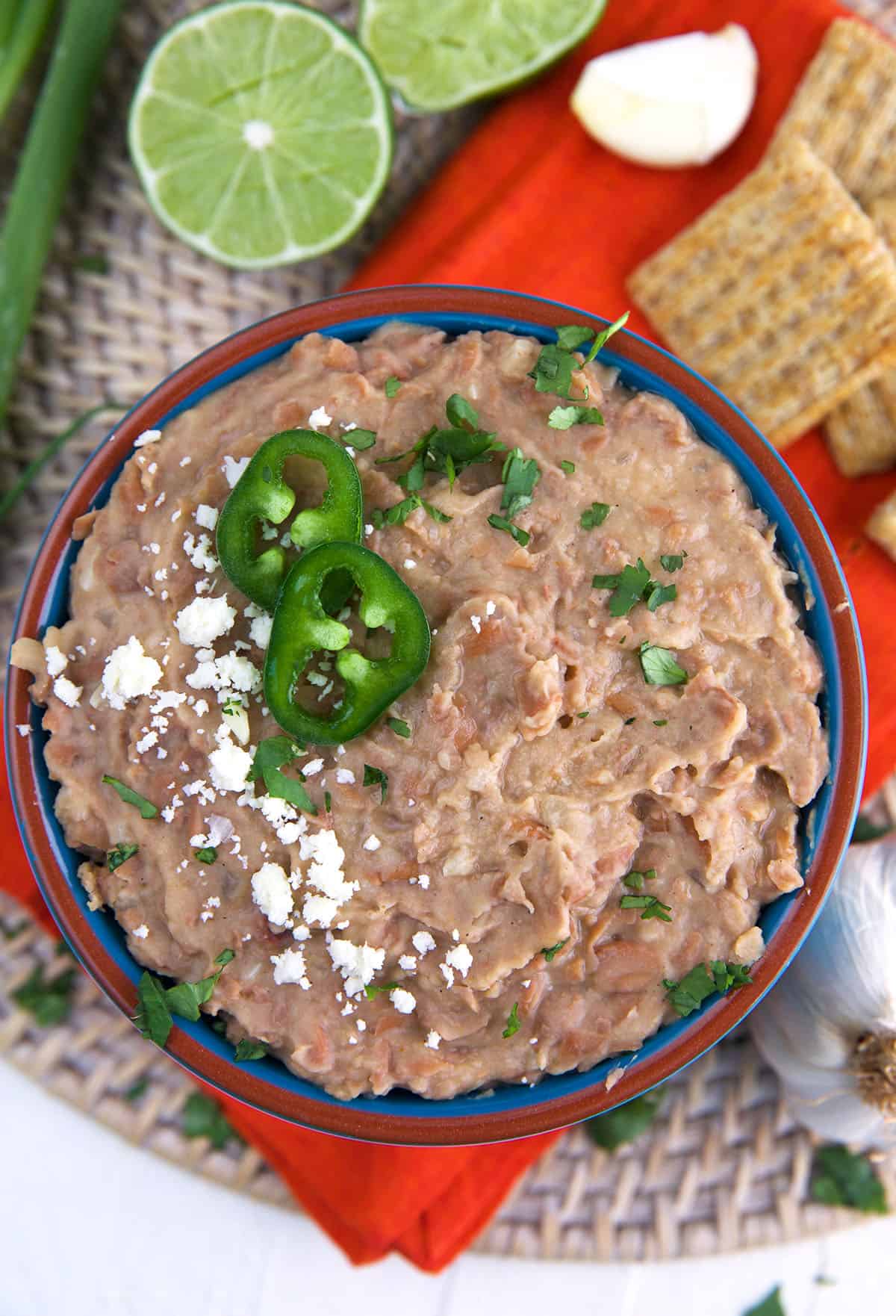 Cilantro, cheese and jalapenos garnish a bowl of refried beans.