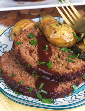 Sliced meatloaf is plated next to roasted potatoes.