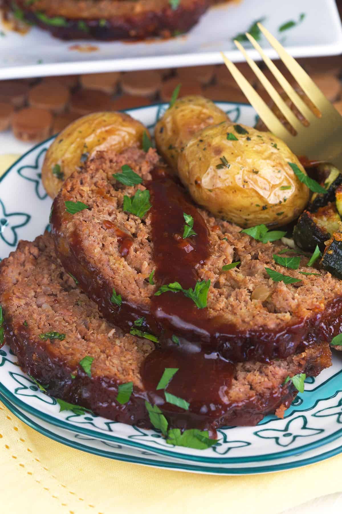 Sliced meatloaf is plated next to roasted potatoes.