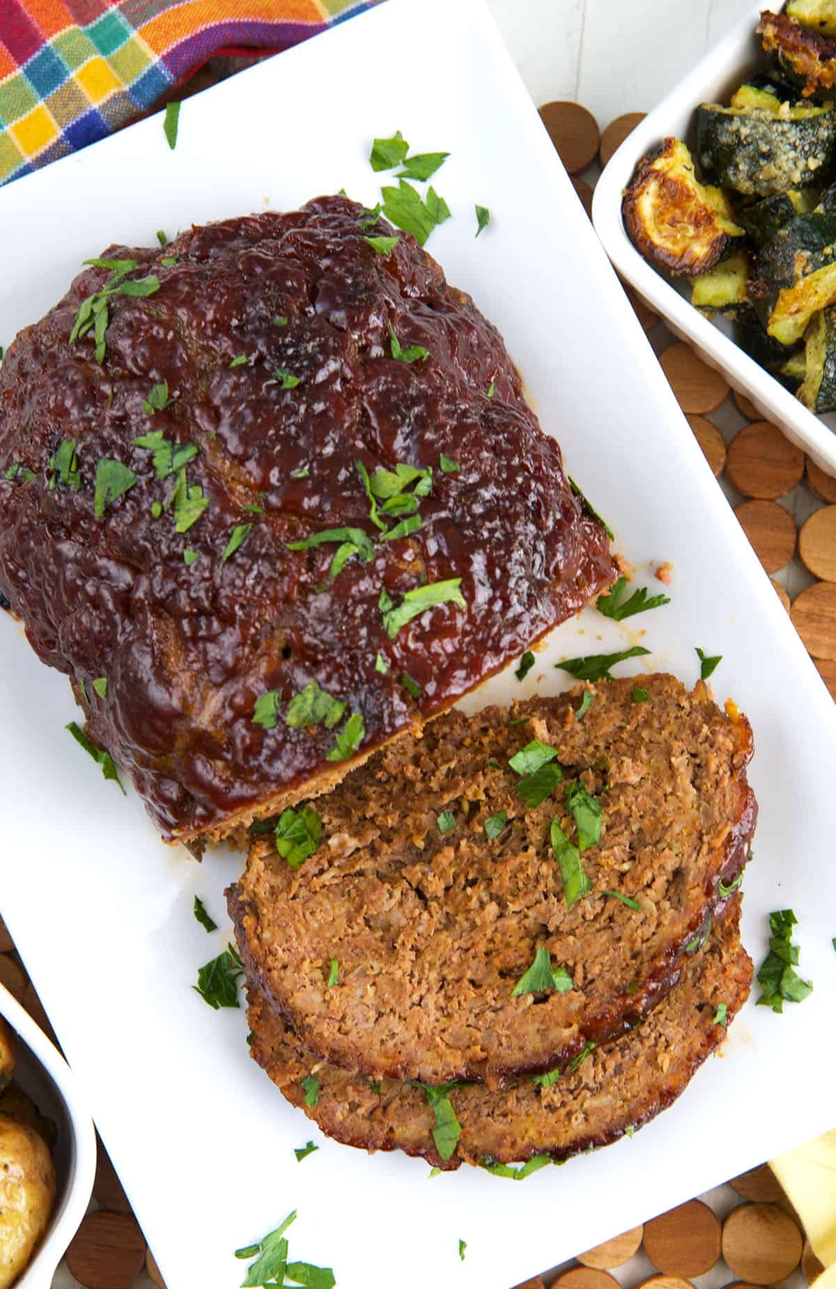 A baked meatloaf is partially sliced and placed on a white serving plate.