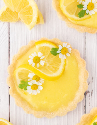 Edible flowrs and lemon twists garnish a mini lemon tart.