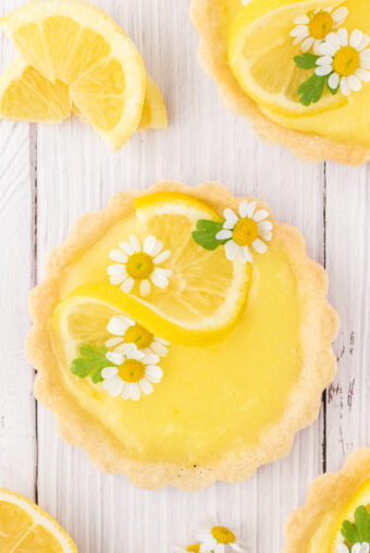 Edible flowrs and lemon twists garnish a mini lemon tart.