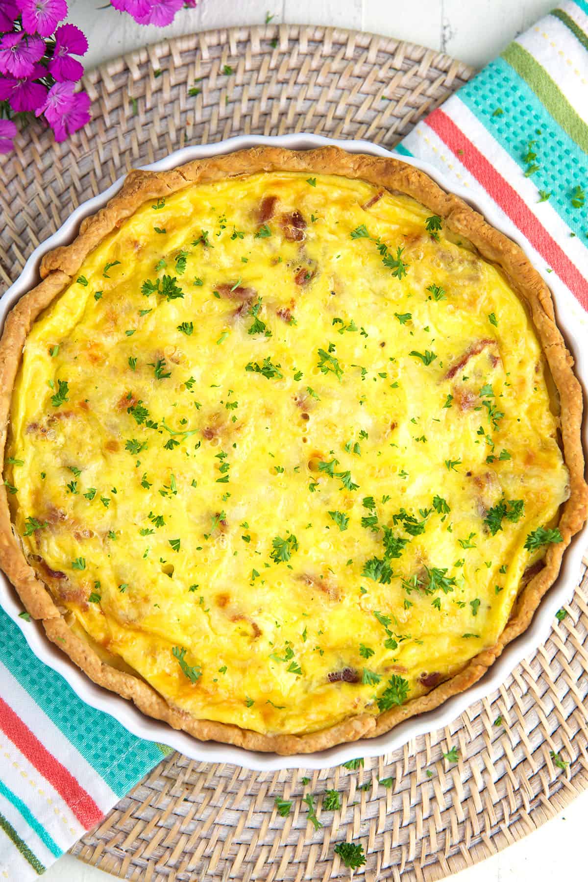 A fully baked quiche is garnished with parsley. 