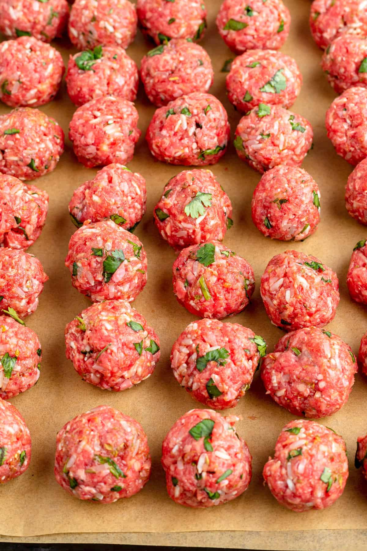 Raw meatballs are placed on a baking sheet.