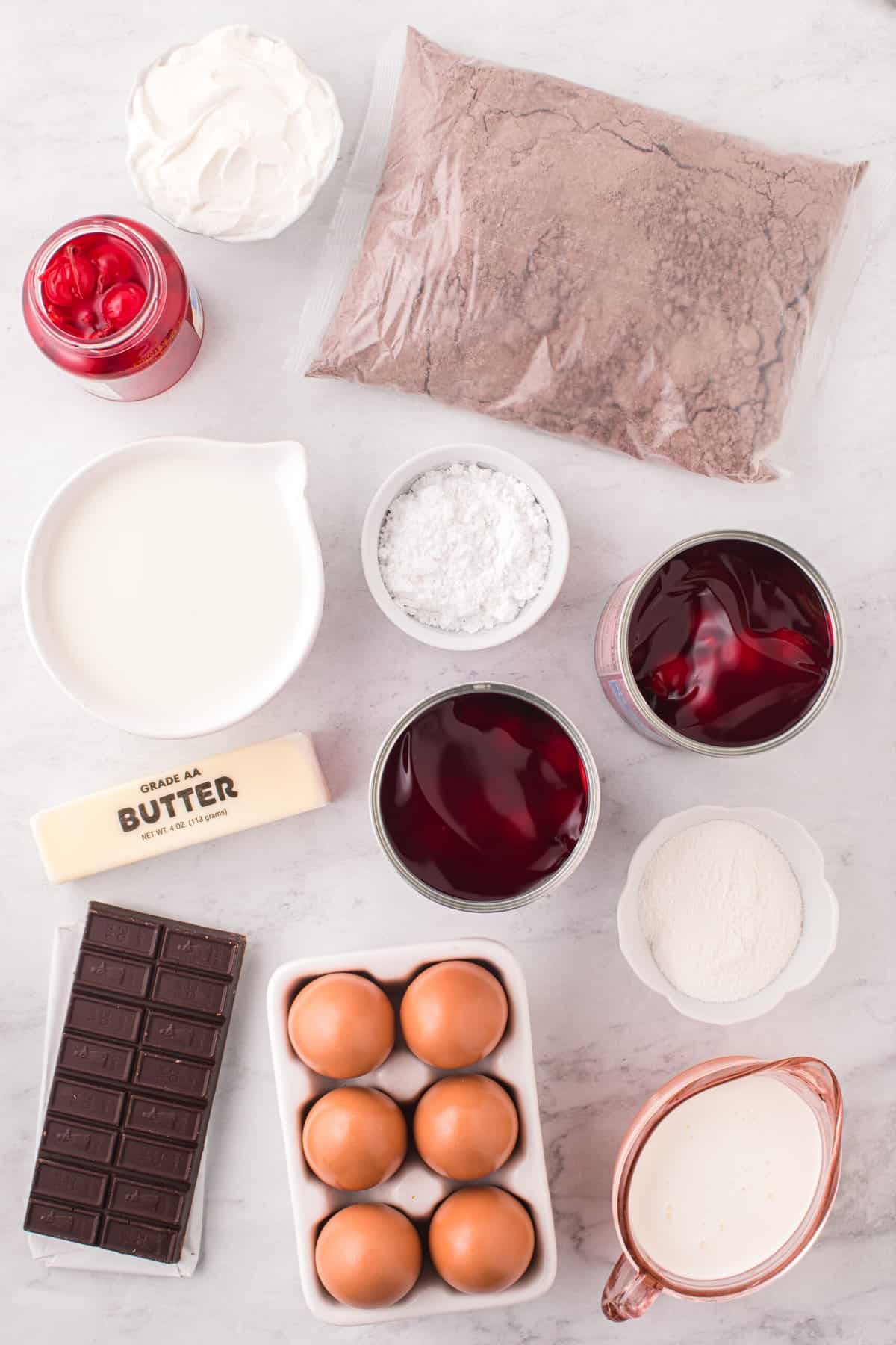 The ingredients for black forest cake are placed on a white surface. 