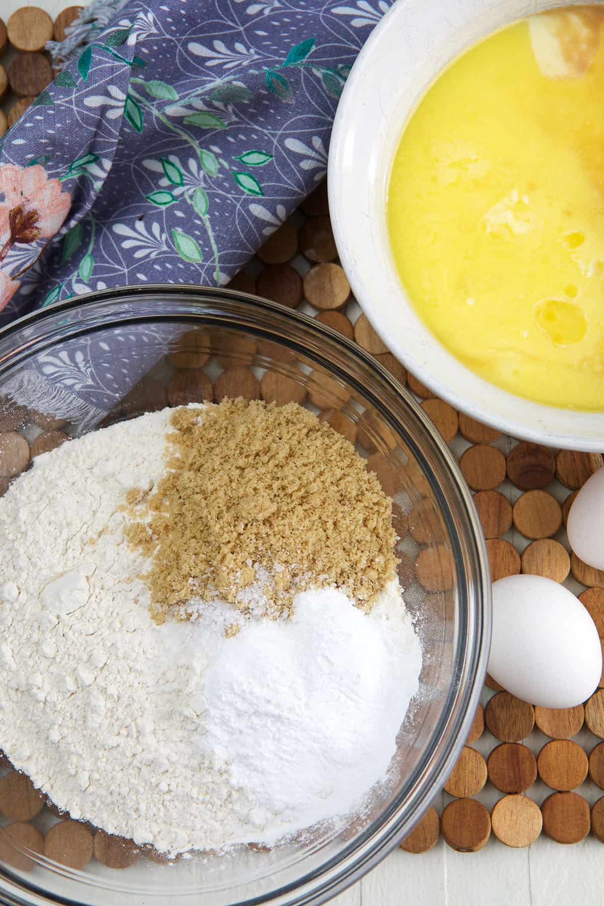 A bowl of wet ingredients is placed next to a bowl of dry ingredients. 