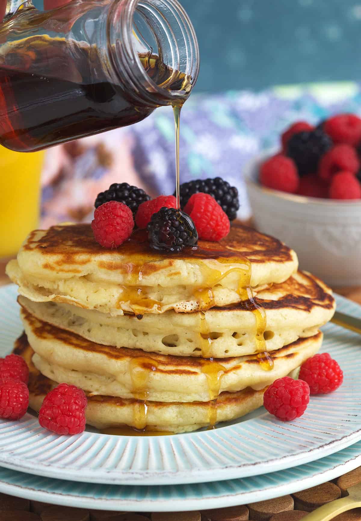 A stack of pancakes is being topped with maple syrup. 