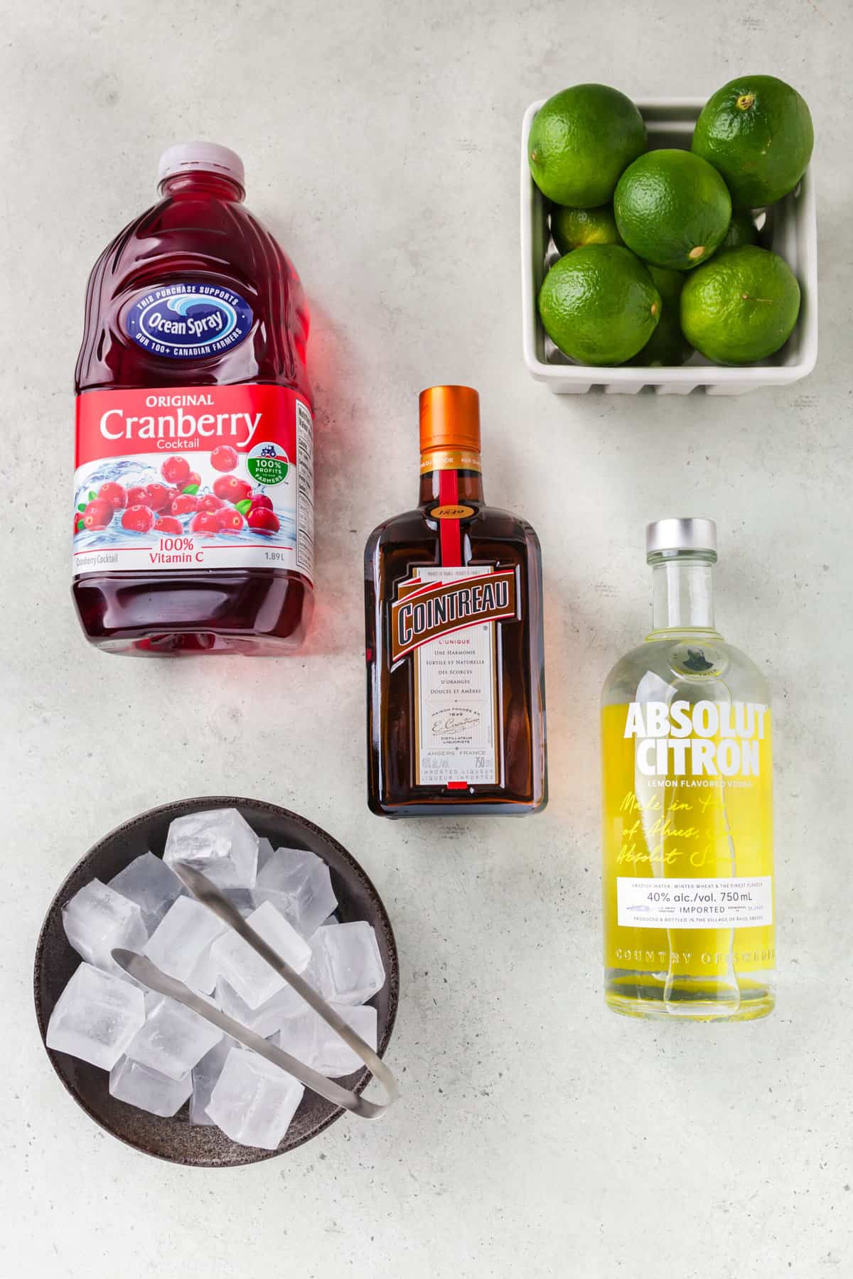 The ingredients for cosmopolitans are placed on a white surface.