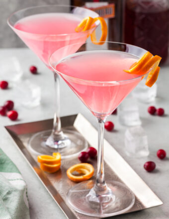 Two martini glasses are filled with pink cosmos.