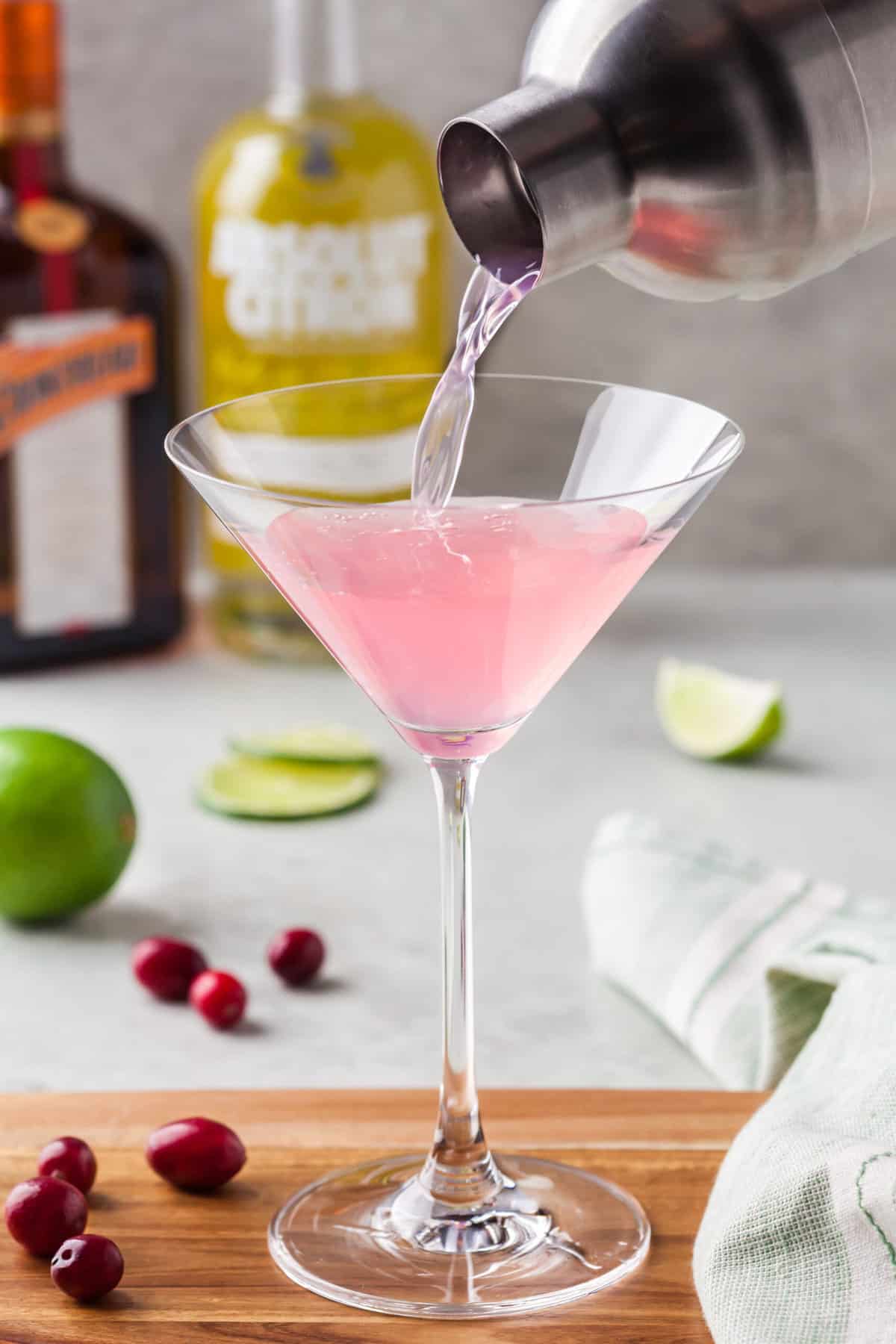 A cosmo is being poured into a martini glass.