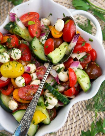 A white dish is filled with cucumber tomato salad.