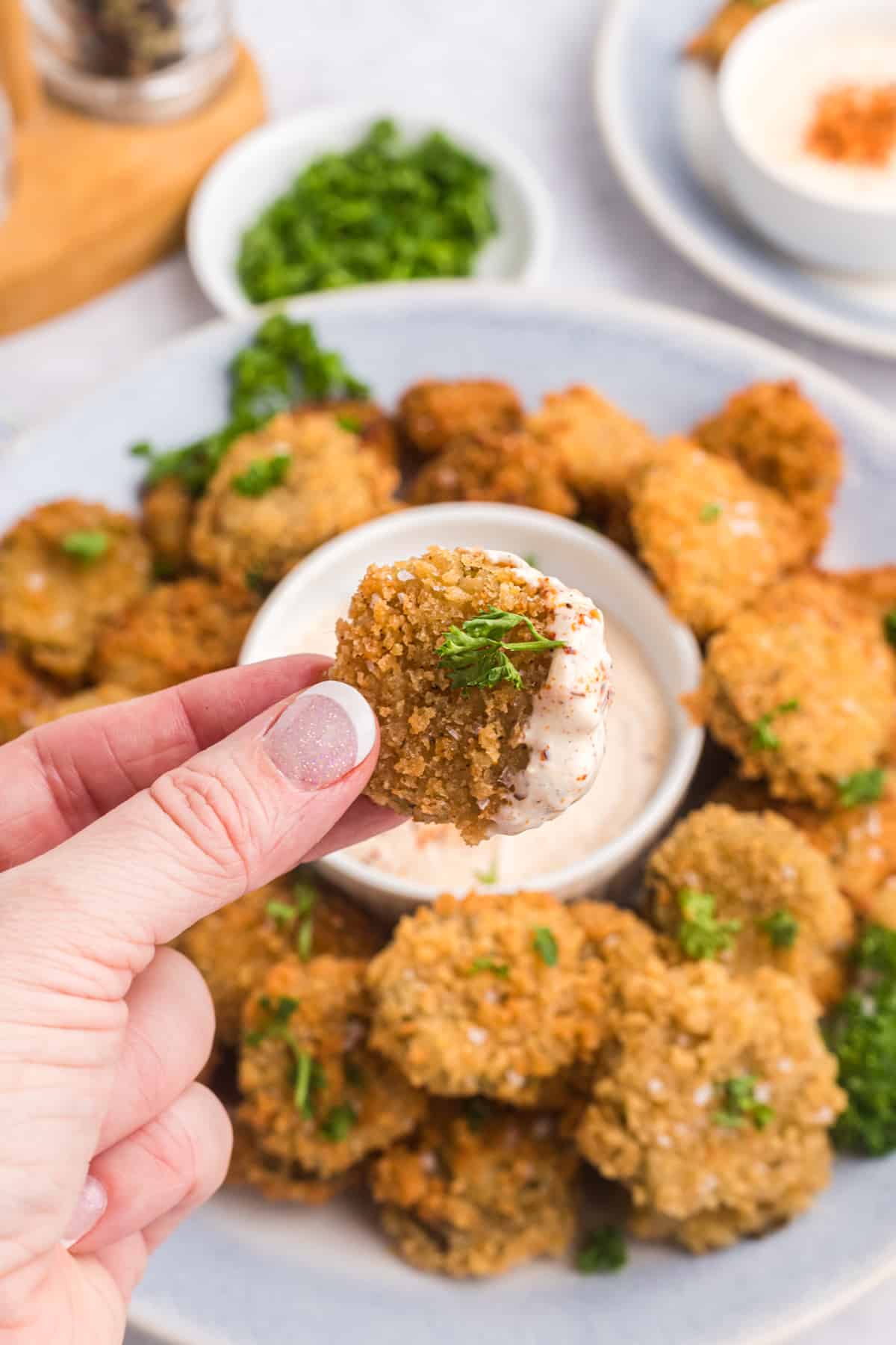 A fried pickle has been dipped in spicy remoulade sauce.