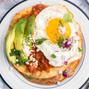 Huevos Rancheros on a white plate with avocado slices on top