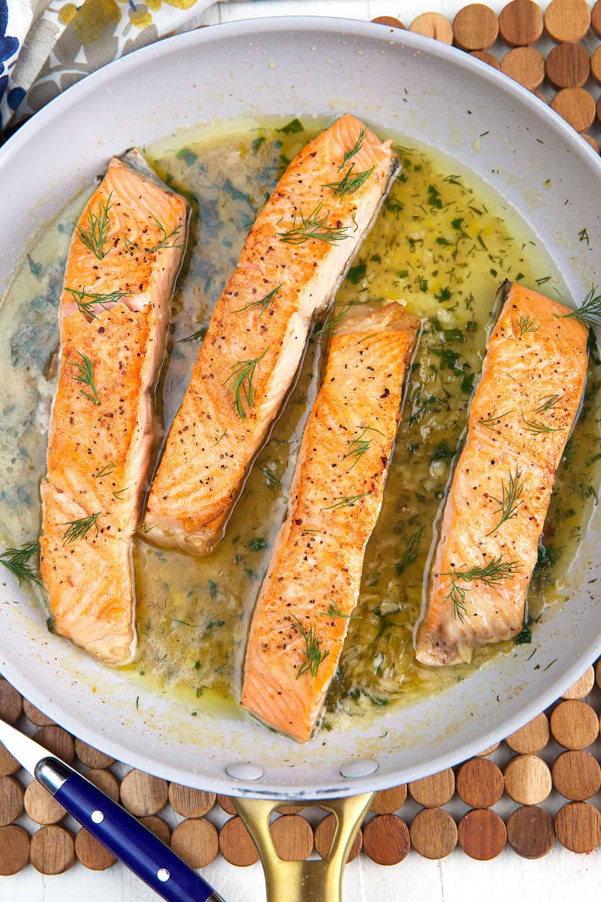 Four salmon filets are being cooked in a skillet. 