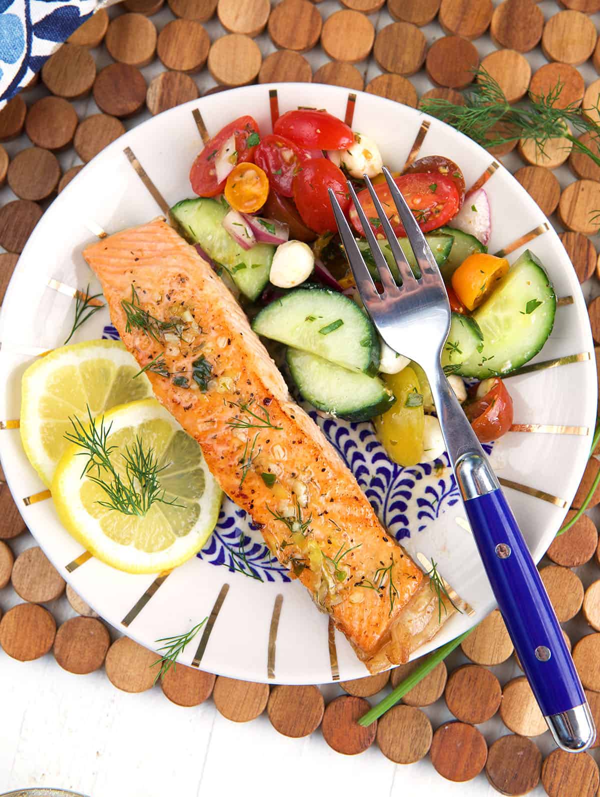 A fork is placed on a plate with veggies and salmon. 