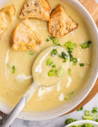 A spoon is placed in a bowl of potato leek soup.