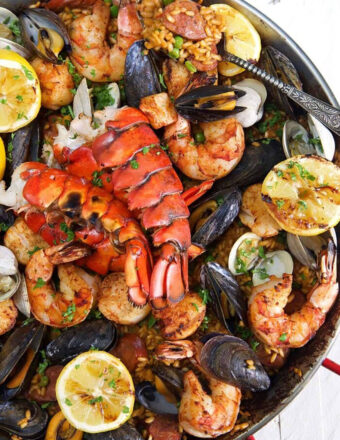 Seafood Paella in a paella pan on a white background.
