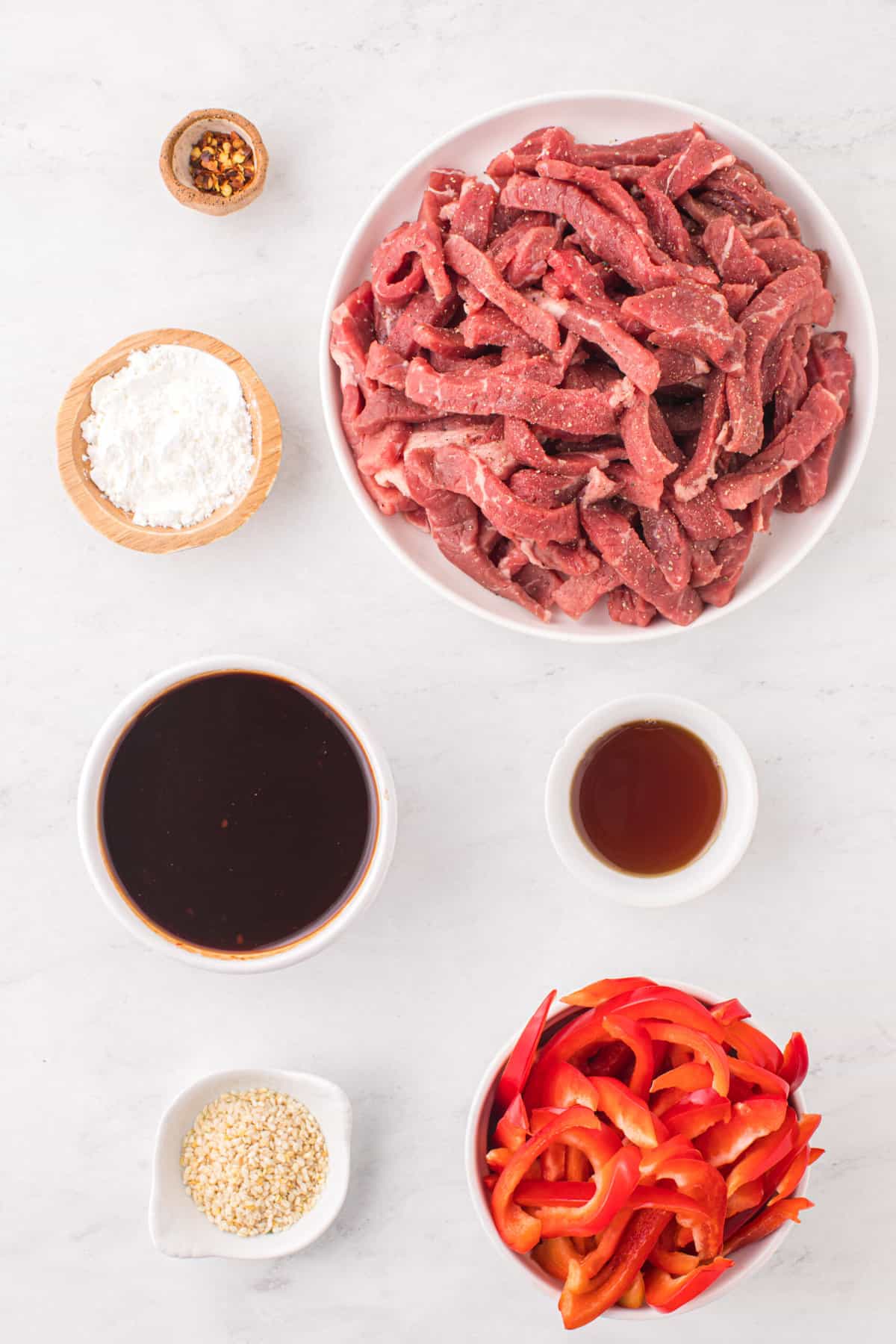 The ingredients for szechuan beef are placed on a white countertop. 