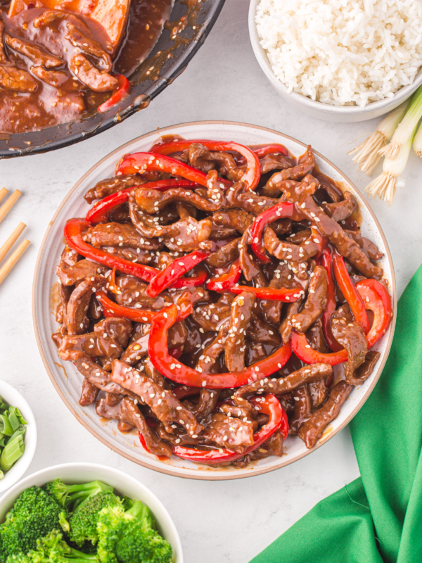 A white plate is topped with szechuan beef.