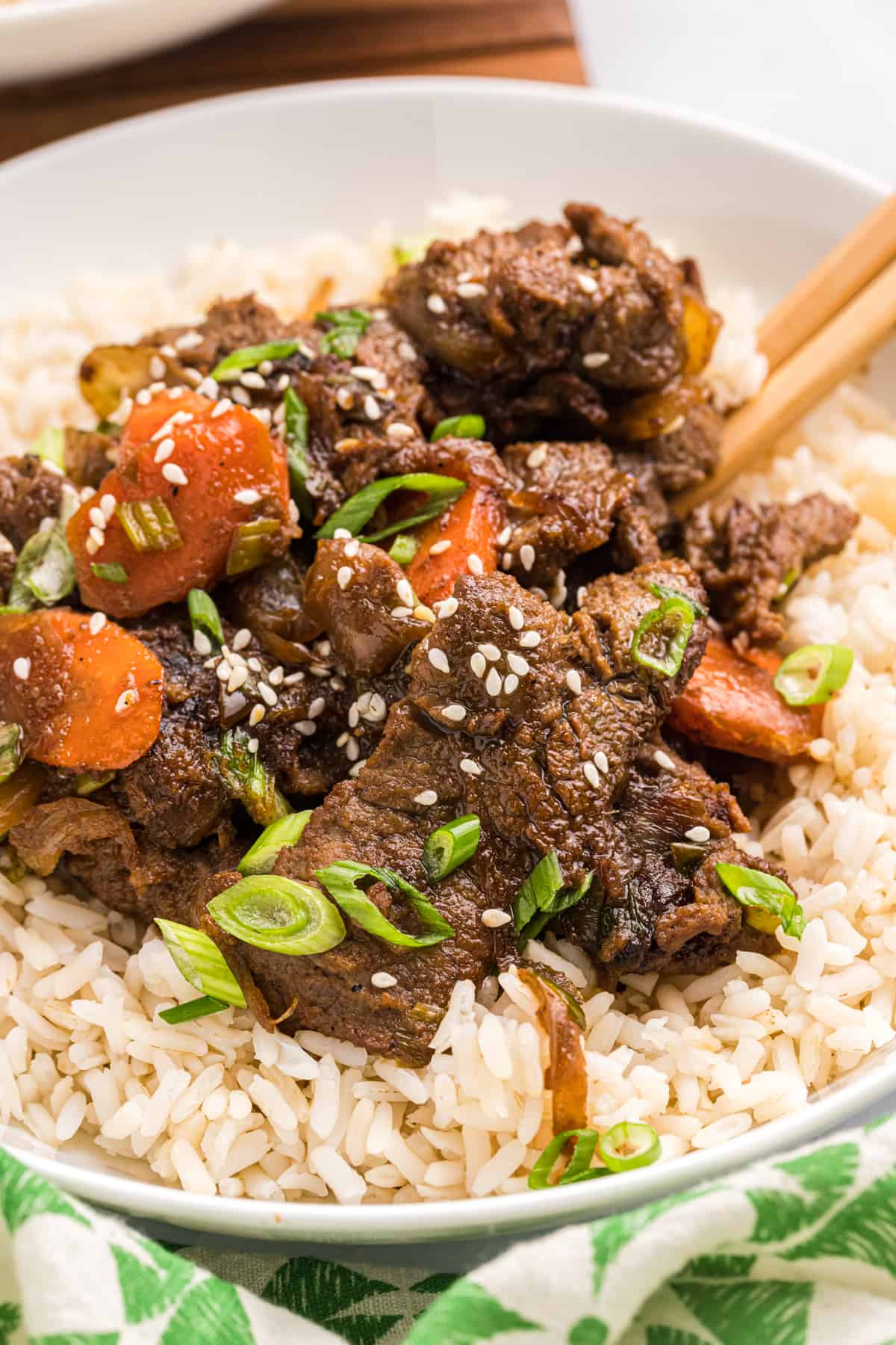 A serving of beef bulgogi is presented on top of rice in a bowl. 