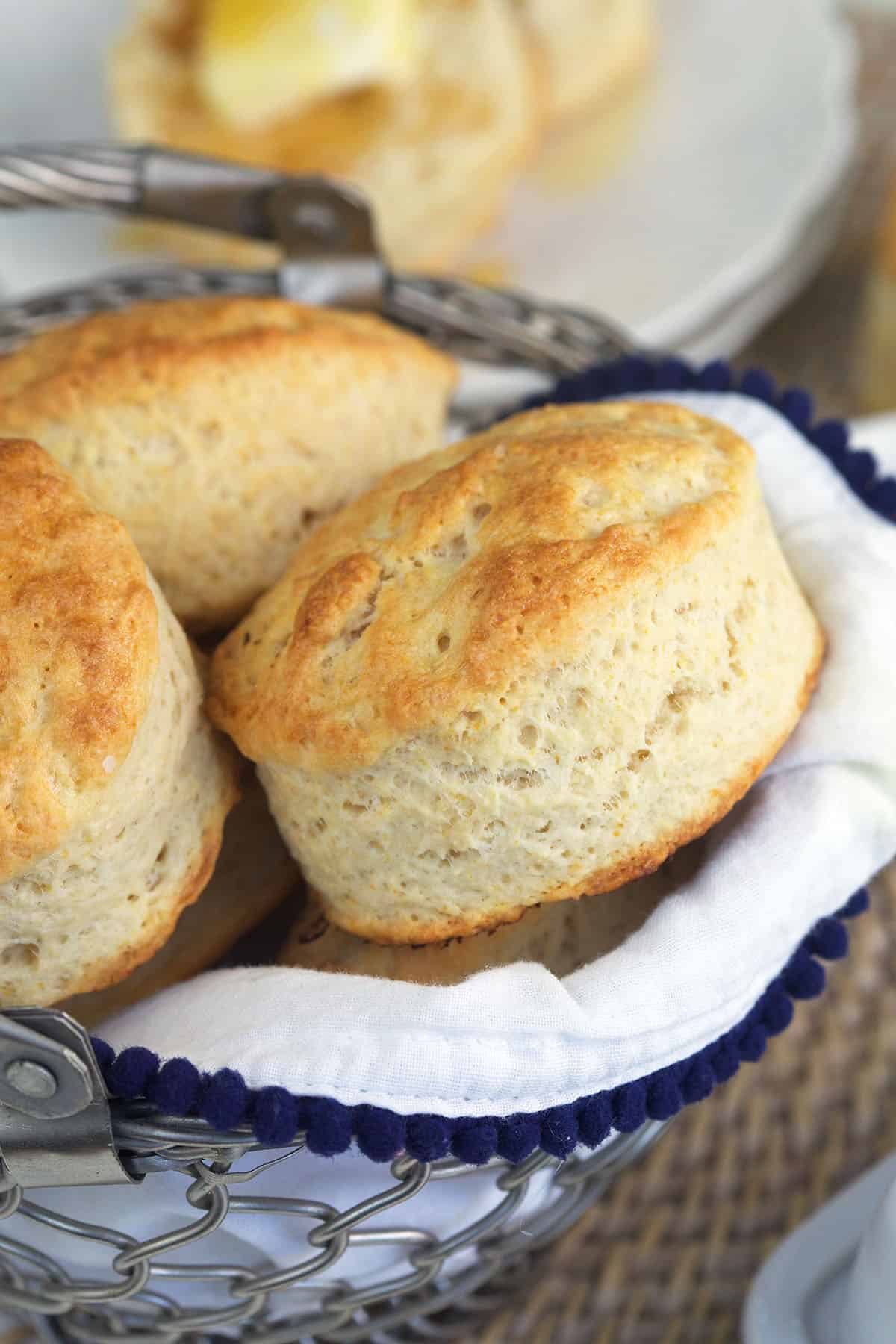 A basket is filled with cooked buttermilk biscuits.