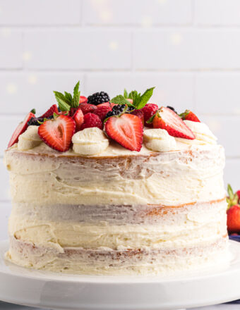 A layered chantilly cake is topped with fresh berries.