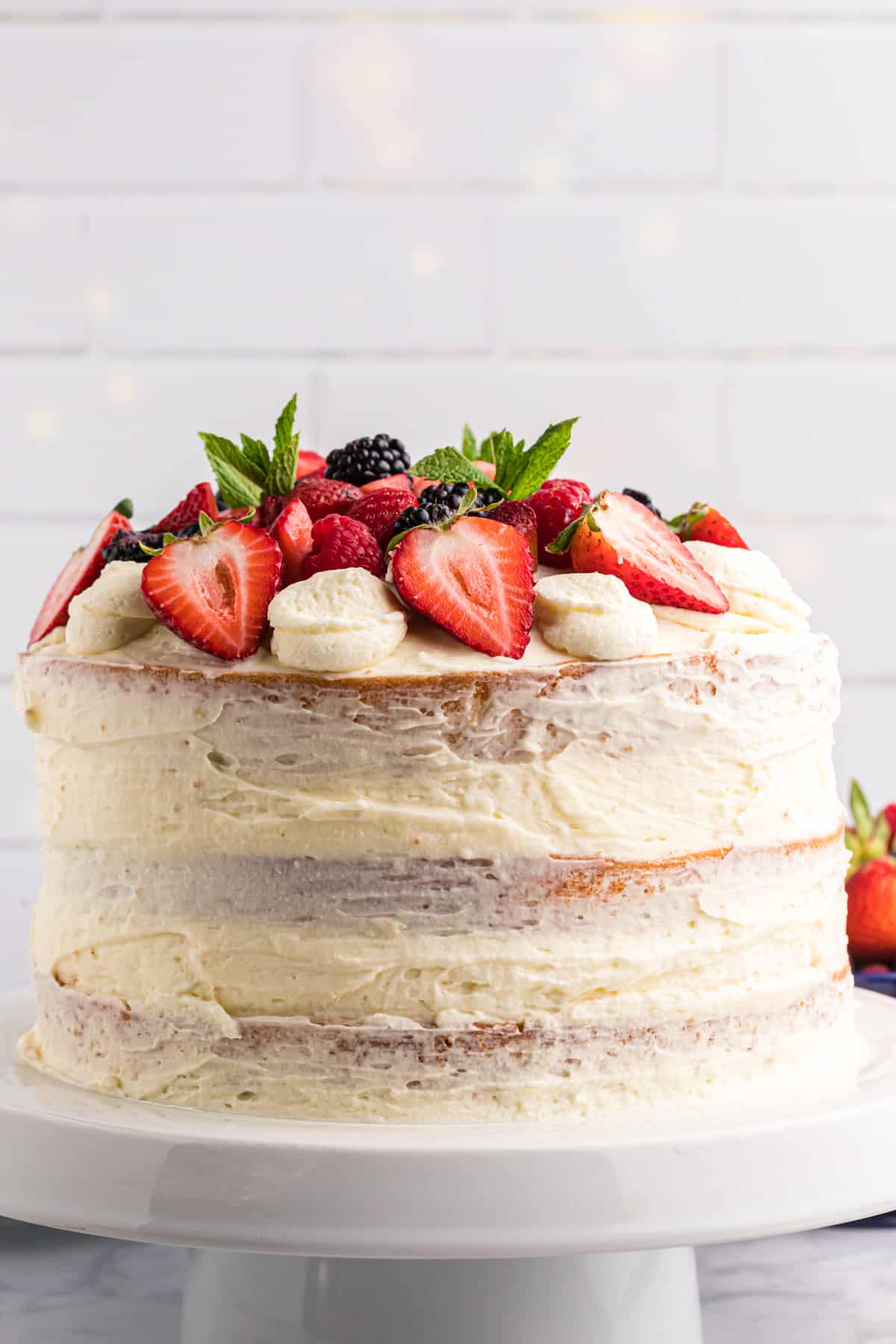 A layered chantilly cake is topped with fresh berries. 