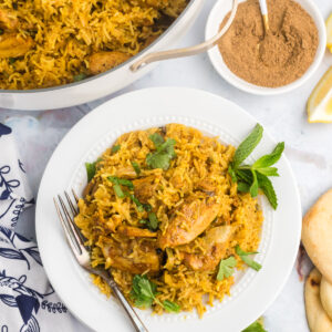 A single serving of chicken biryani is placed next to a skillet.