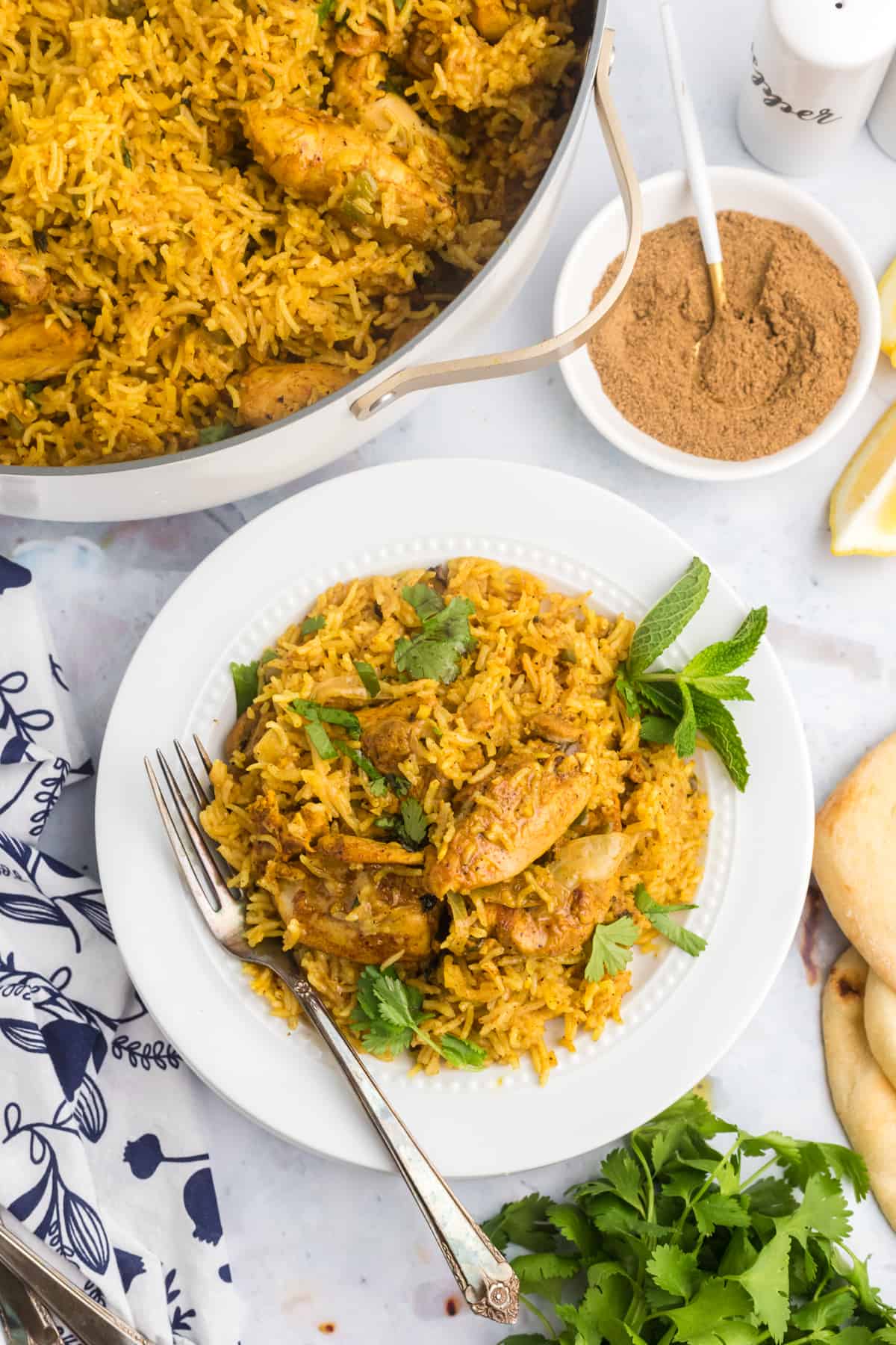 A single serving of chicken biryani is placed next to a skillet. 