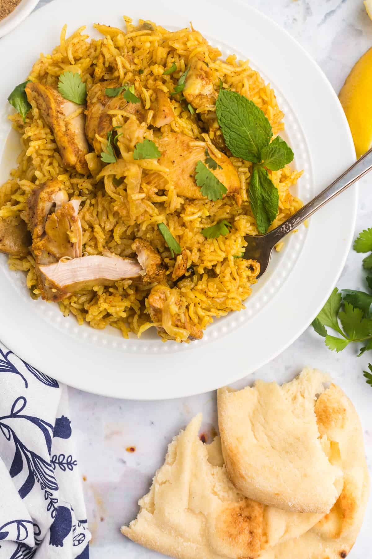 A serving of chicken biryani is placed next to naan bread. 