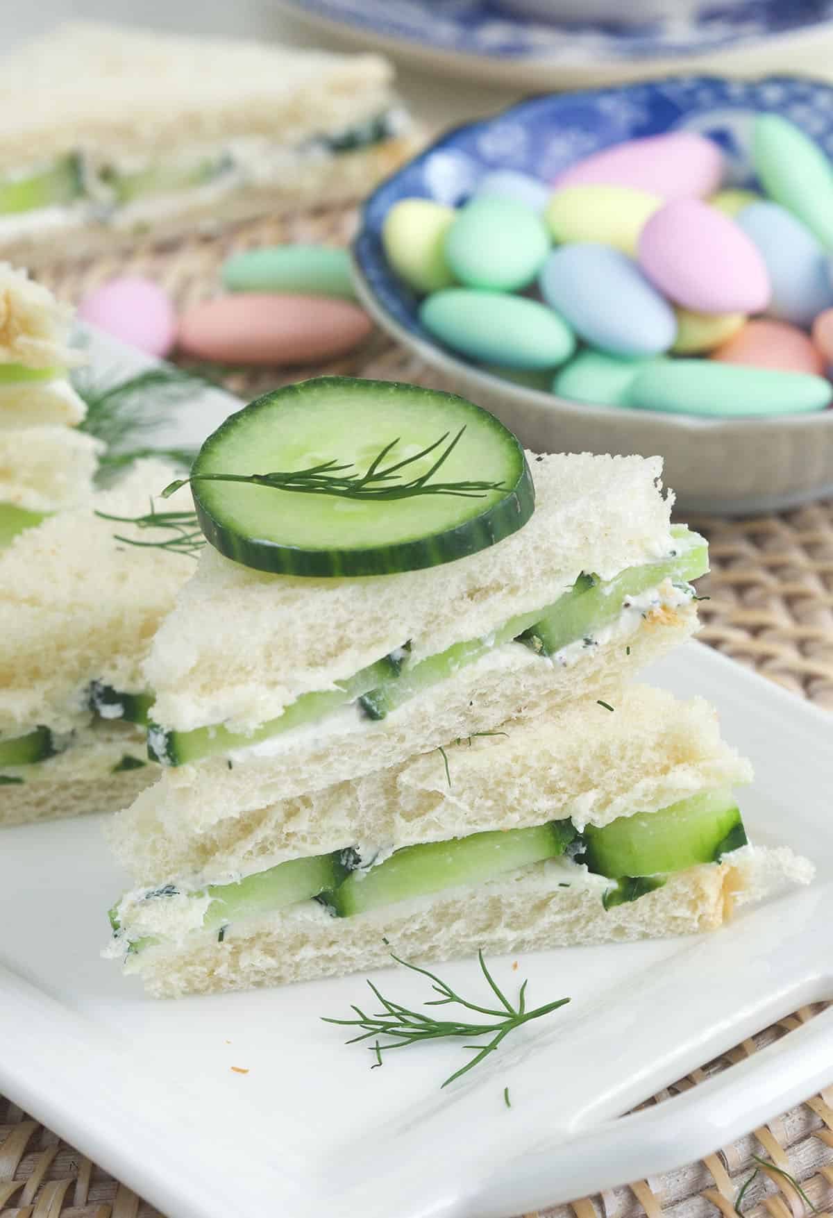 Robins eggs are placed behind stacked cucumber sandwiches. 